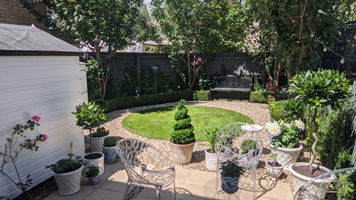 Garden patio with white furniture and well kept plants and grass