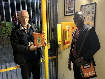 Tim Goodwin and Julian Adje from Stockwell Park Community Trust pose with defibrillator