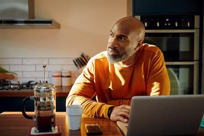 Man sitting in front of laptop at dining table